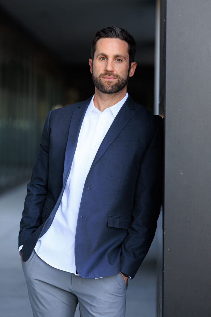 Man in navy blazer leaning against wall